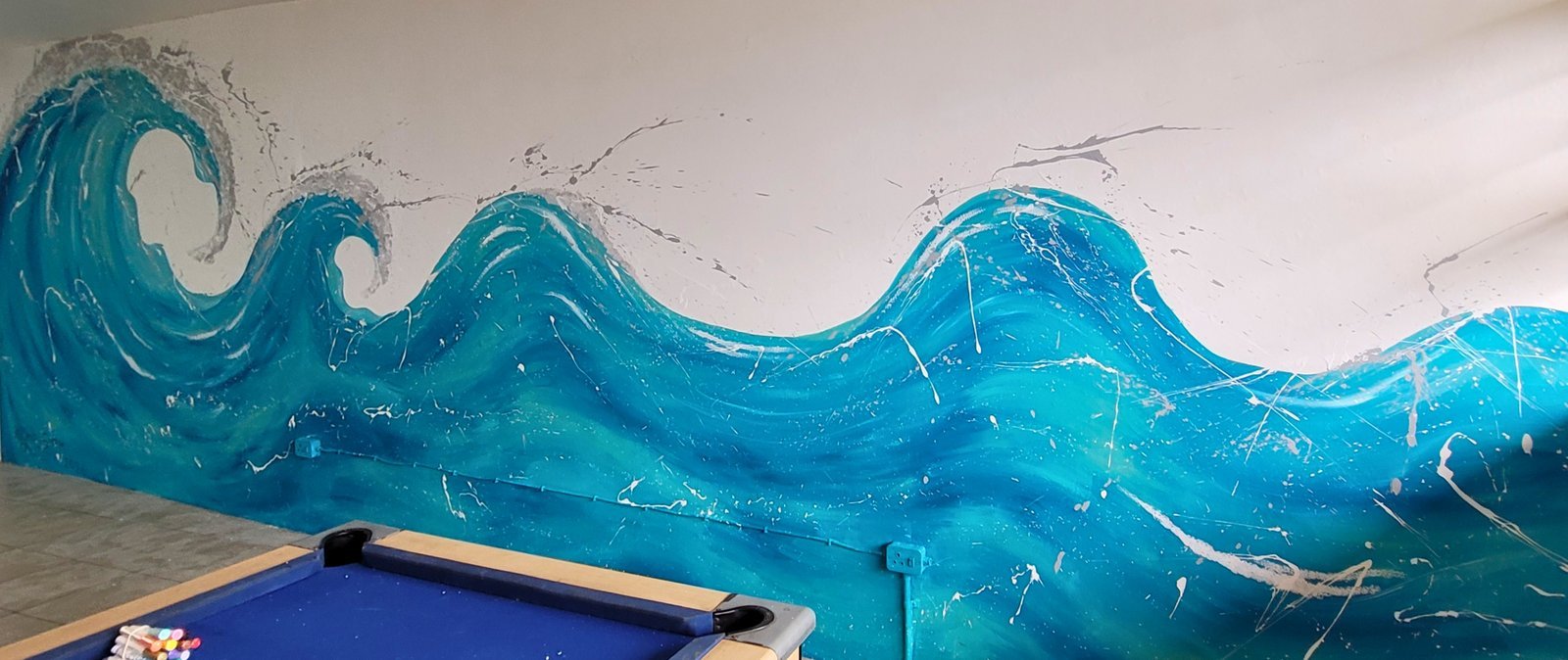 Peacehaven games room with pool table and wave mural